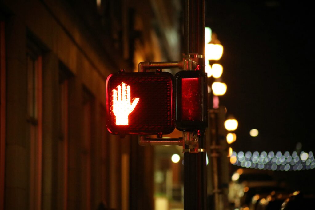 traffic signal at night with red hand signaling don't walk