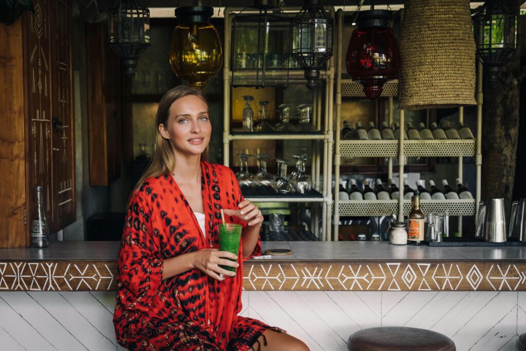 Woman holding a green smoothie sitting at a bar