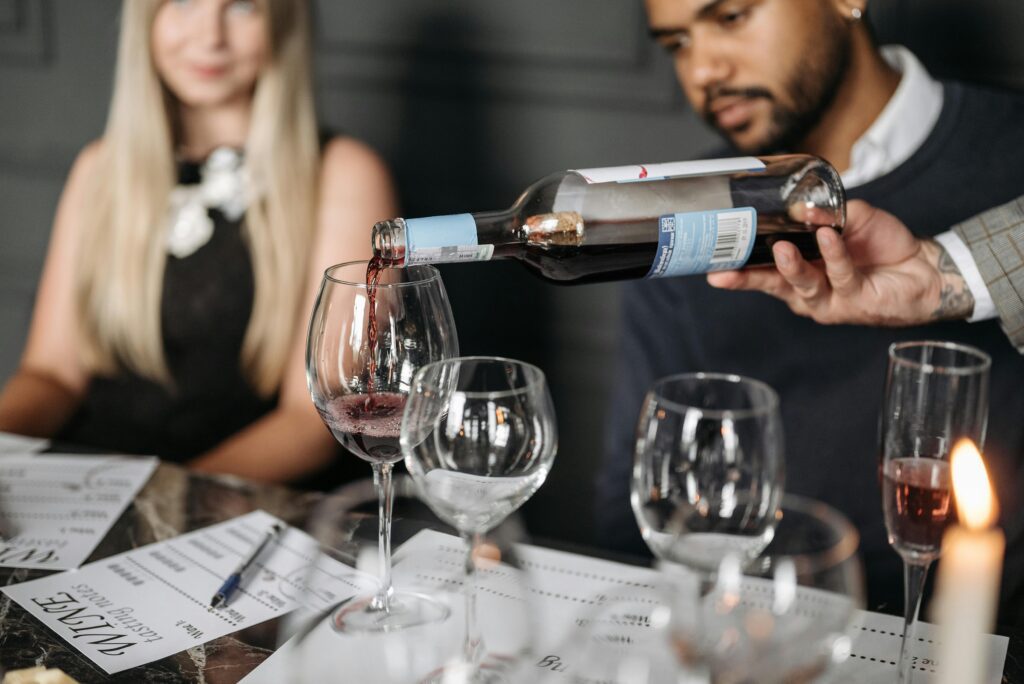 Pouring red wine into a glass at a table with diverse millennials
